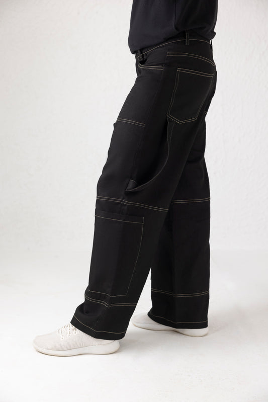 Side view showing vertically hanging thigh belts and large shin pockets on black denim cargo pants