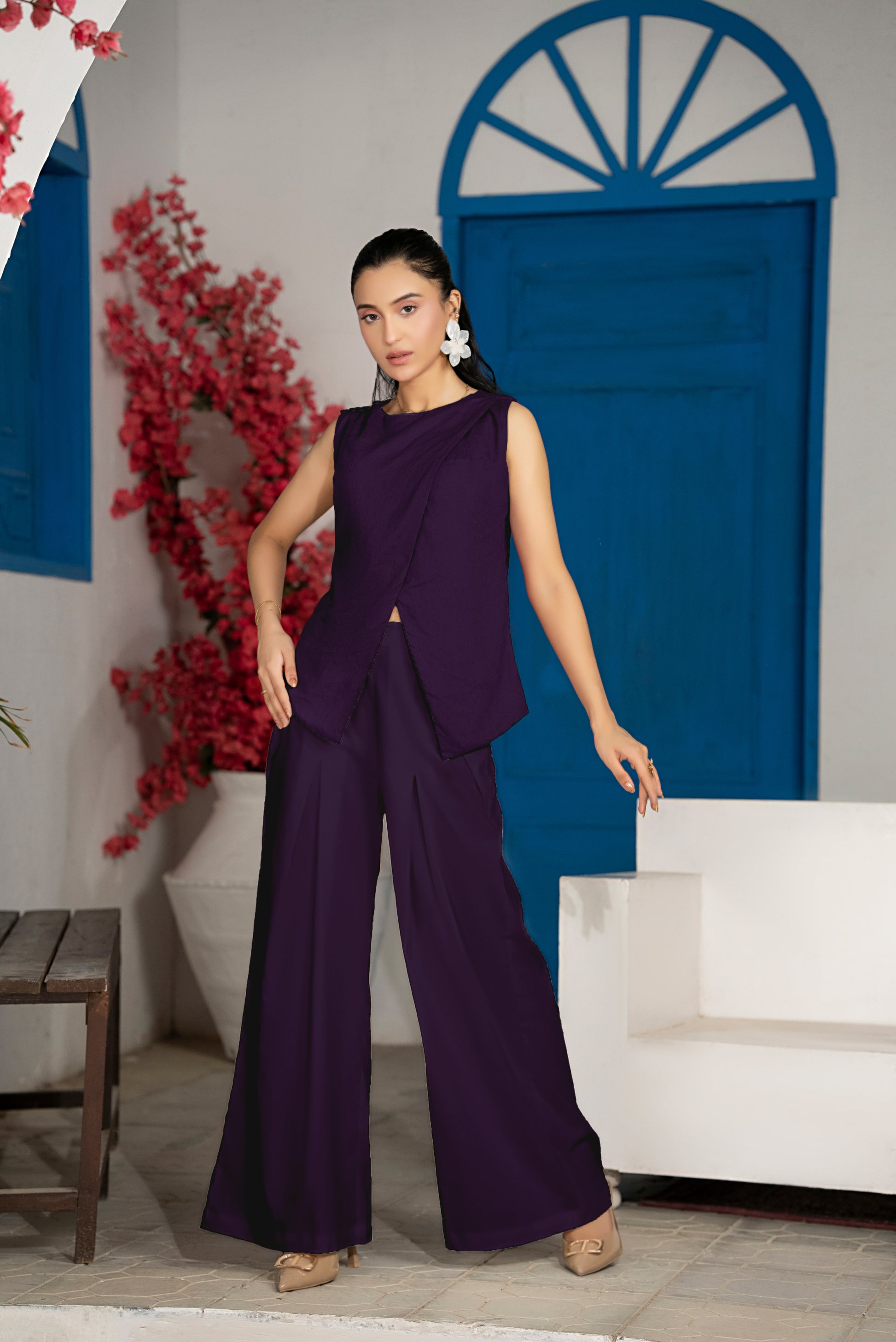 Woman in a purple outfit standing in a room with blue doors and white furniture.