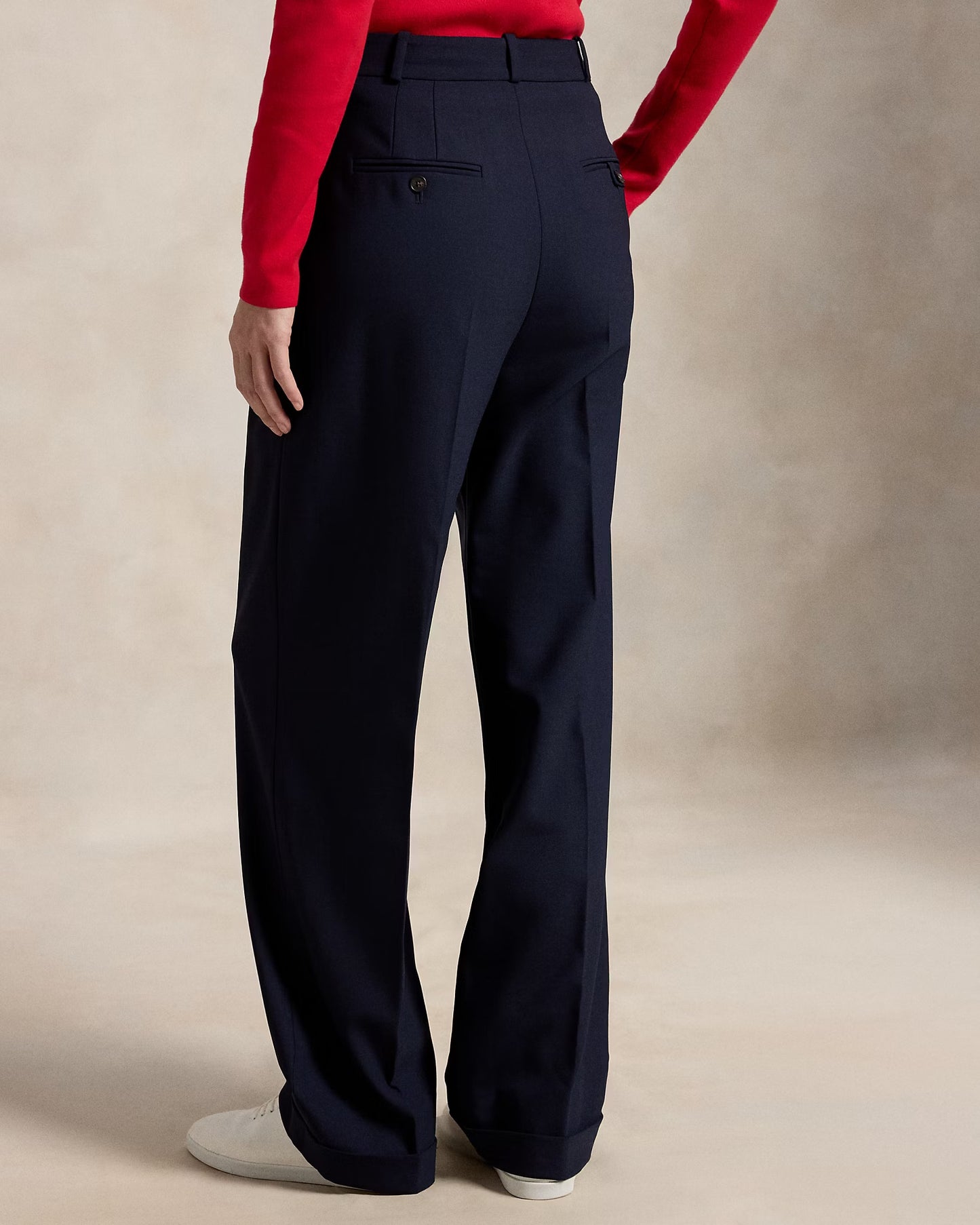 Navy pants worn by a person with a red sweater on a beige background