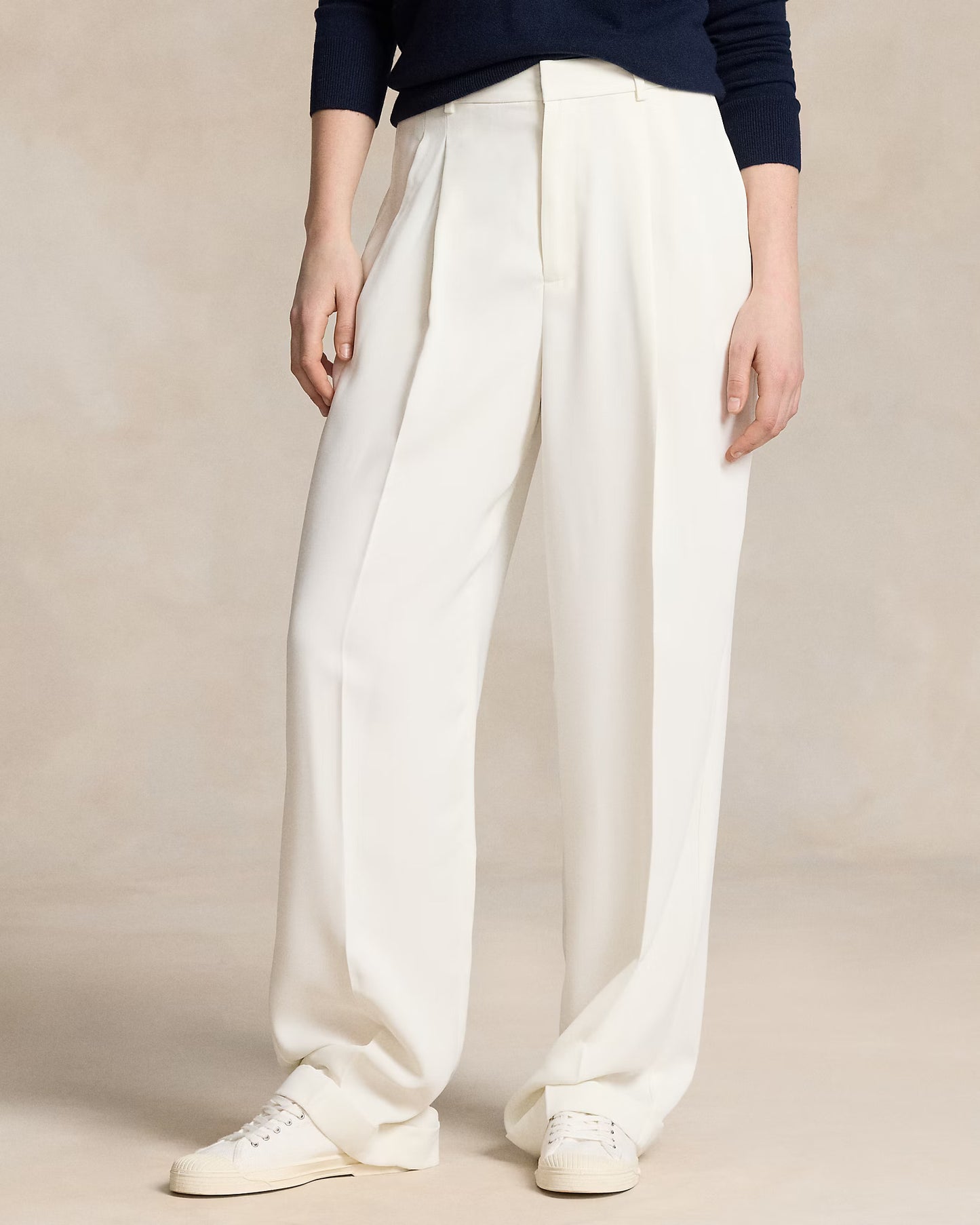 women wearing white wide-leg pants and a navy top on a beige background