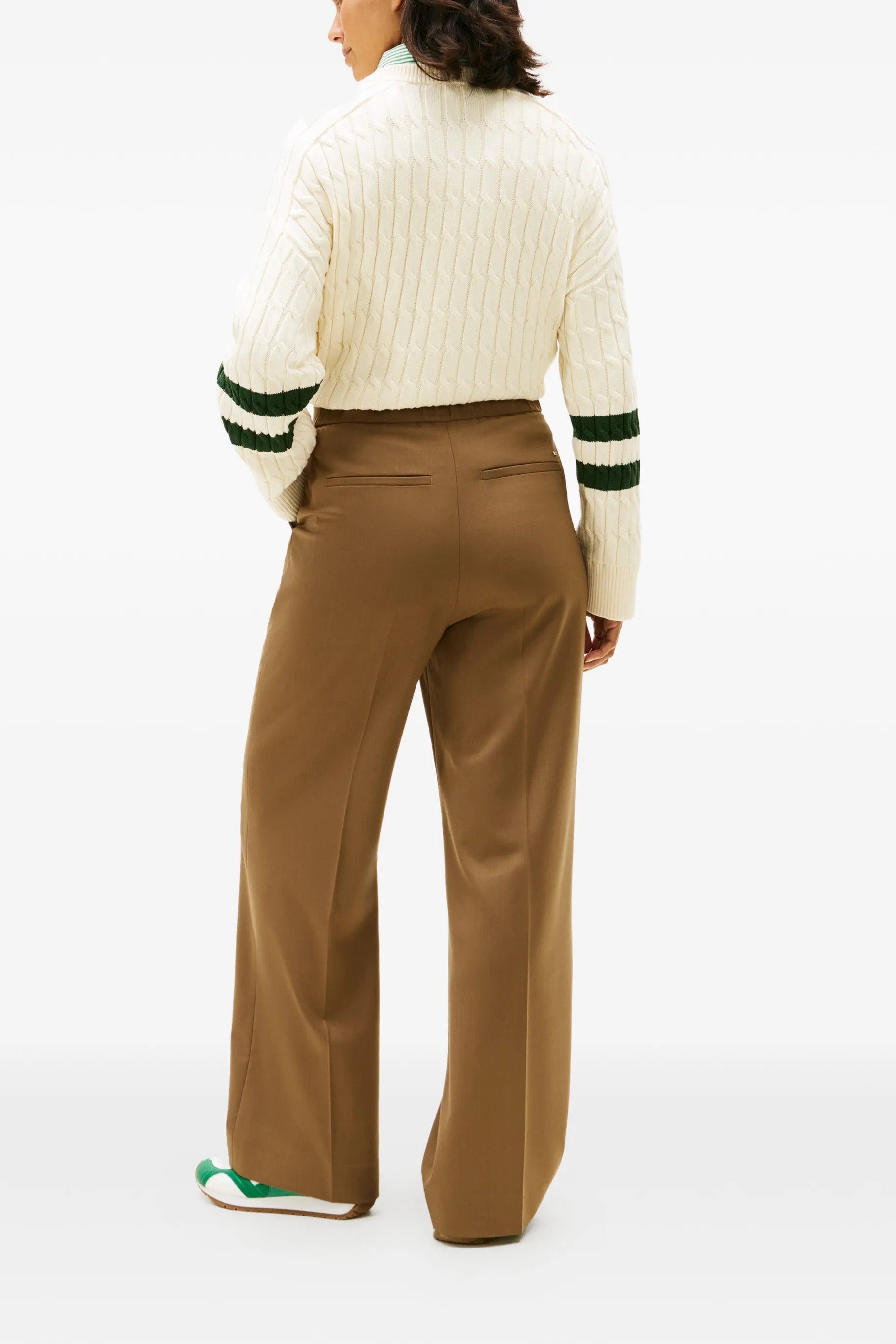 Person wearing brown pleated pants on a white background