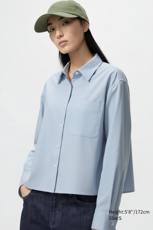 Person wearing a light blue shirt and green cap on a plain background